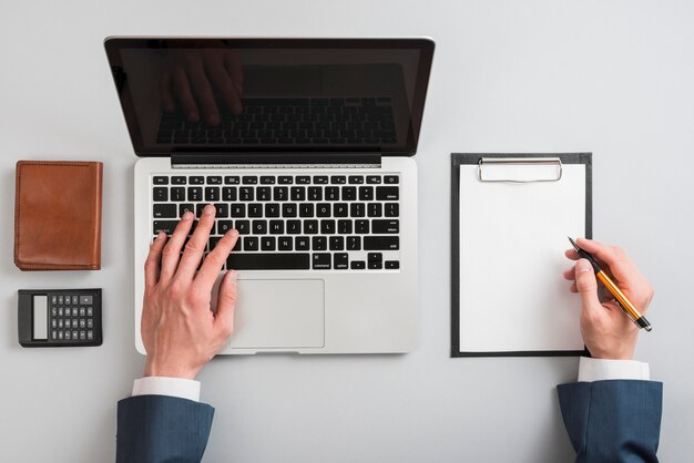 Hand writing on clipboard and laptop