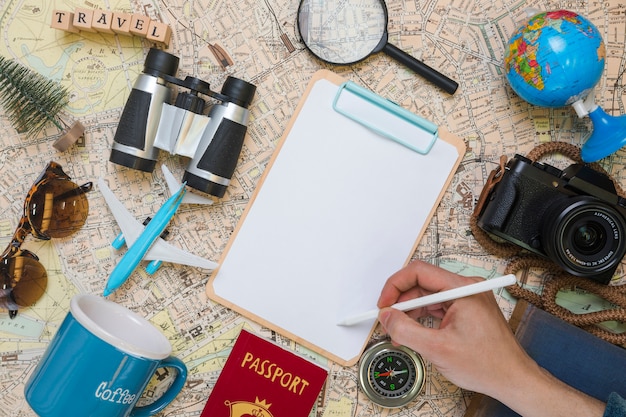 Hand writing on folder surrounded by travel elements