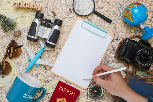 Hand writing on folder surrounded by travel elements