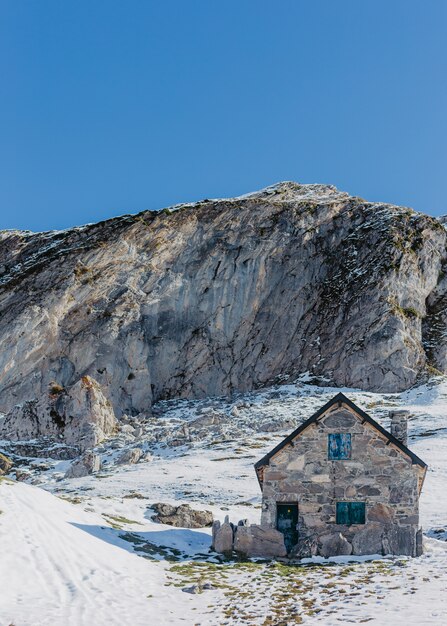 Handbuilt grey stone house with high rocks and beautiful clear blue sky in the background