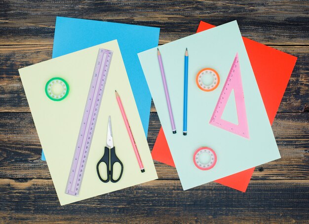 Handcraft concept with papers, rulers, scissors, pencils, tapes on wooden background flat lay.