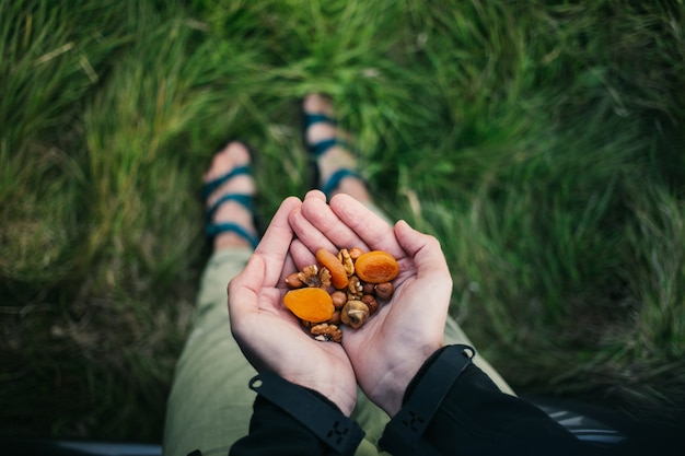 Foto gratuita una manciata di noci sane, uvetta e frutta secca all'aperto nella natura selvaggia. spuntino veloce durante l'escursione in montagna.