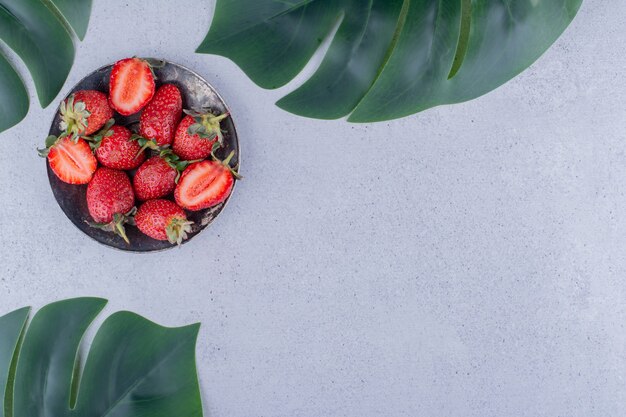 Handful of strawberries and decorative leaves on marble background. High quality photo