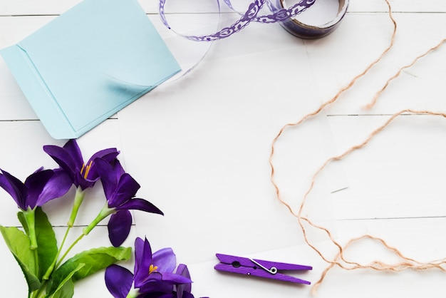 Бесплатное фото Искусственные фиолетовые цветы ручной работы; бумага; ленты; прищепка и веревка на фоне белой доски