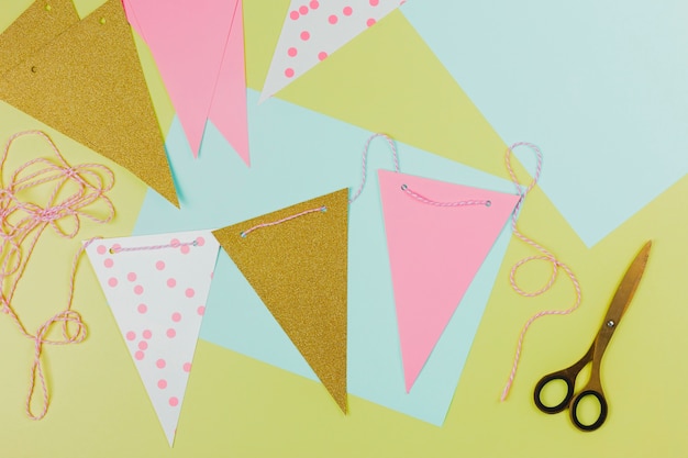 Free photo handmade colorful bunting made with paper and scissor on green background