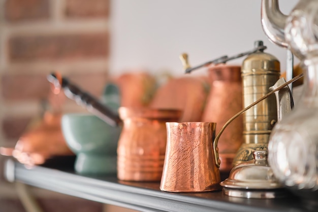 Free photo handmade copper cezve turkish traditional tableware on a shelf in the kitchen at home or in a restaurant selective focus
