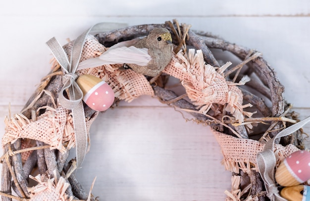 Пасхальный венок ручной работы из веточек и лент с милой птичкой и деревянными яйцами Premium Фотографии