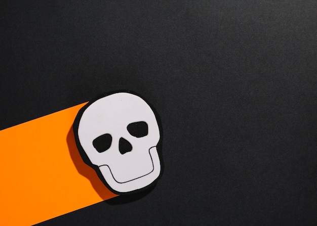 Handmade Halloween skull on orange stripe of paper