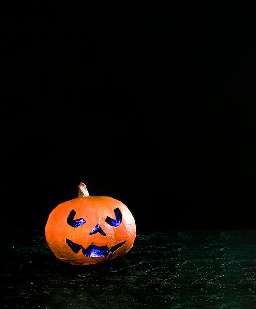 Handmade orange pumpkin in Halloween style with angry carved face illuminated inside