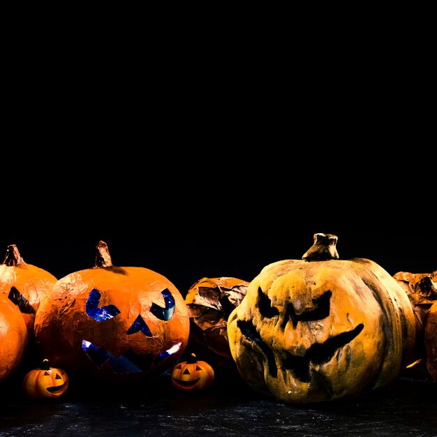 Handmade orange pumpkins with carved faces and illuminated and black inside