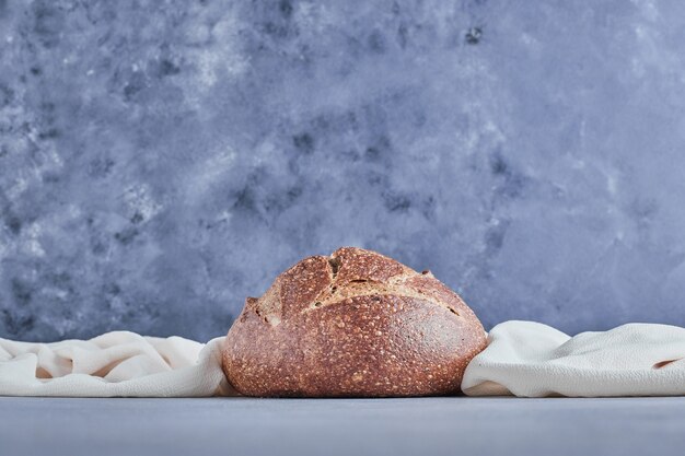 Handmade round bread bun on blue table.