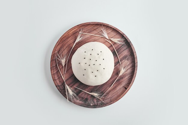 Тесто для круглых булочек ручной работы на деревянной тарелке.