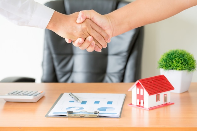 Руки агента и клиента пожимают друг другу руки после подписания договора на покупку новой квартиры.