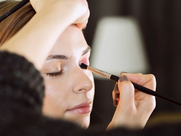 Hands applying eye makeup close up