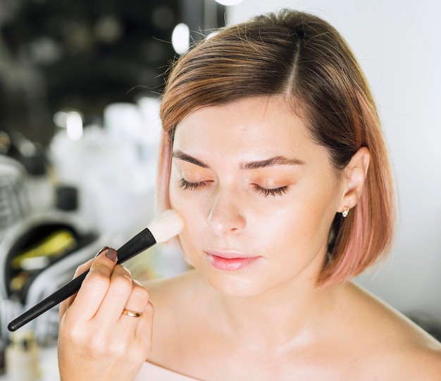 Hands applying makeup by brush