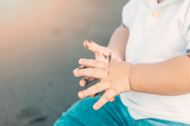 Hands of baby dirtying by beach sand 