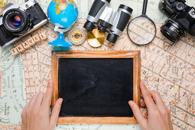 Hands on blackboard surrounded by travel elements