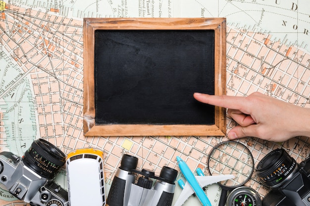 Free photo hands on blackboard surrounded by travel elements