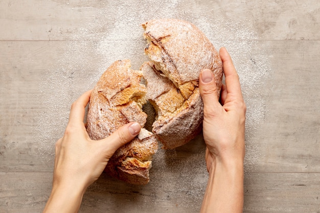 Foto gratuita mani che spezzano un delizioso pane