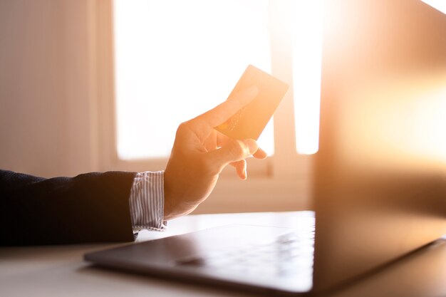 Hands of a businessman using laptop and card on the internet