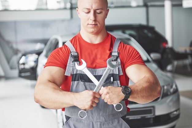 Hands of car mechanic with wrench in garage.