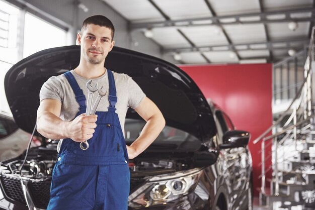 Hands of car mechanic with wrench in garage.