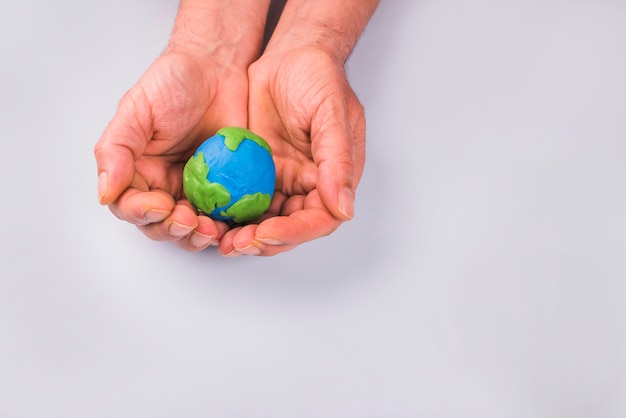 Hands of child holding colorful clay model of planet earth