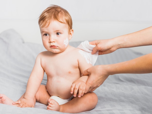 Hands cleaning baby with baby wipe