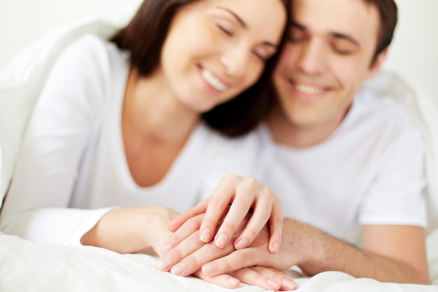 Hands close-up of a couple in bed