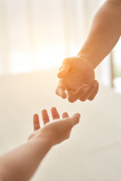 Hands of couple extended to each other against the sunlit room