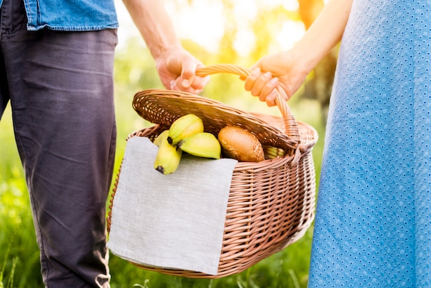 Hands of couple holding picnic basket full of food