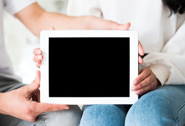 Free photo hands of couple holding white tablet on knees