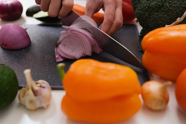 Руки режут лук на разделочной доске овощи крупным планом