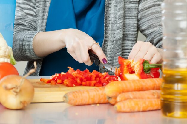 Руки разрезают овощи на разделочной доске