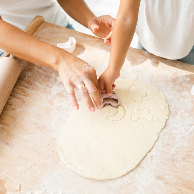 Hands cutting dough for cookies