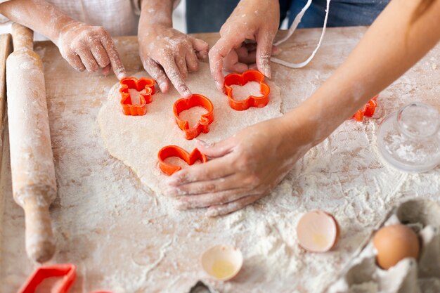 Hands cutting dough with cookie forms