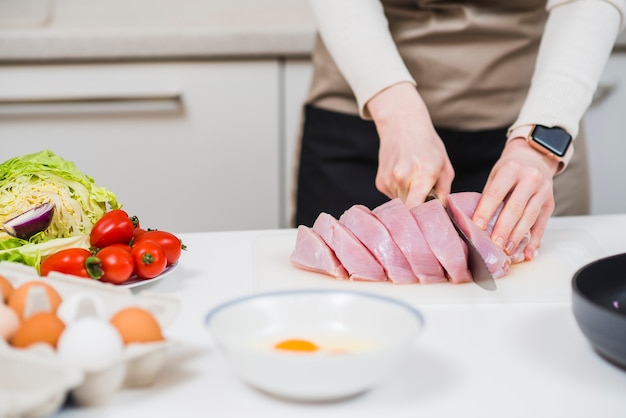 Hands cutting raw meat on table