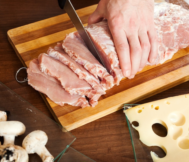 Hands cutting raw meat