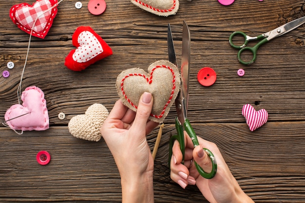 Hands cutting a red heart shape on wooden background