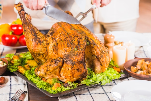 Hands cutting roasted chicken on tray 