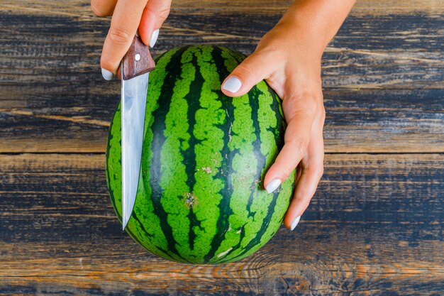 Hands cutting watermelon with knife