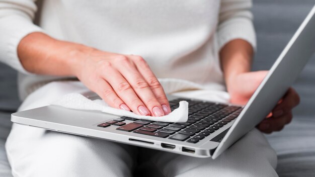 Hands disinfecting laptop surface