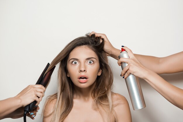 Hands doing hairstyle to young beautiful woman