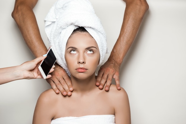 Hands doing massage and giving phone to young beautiful woman