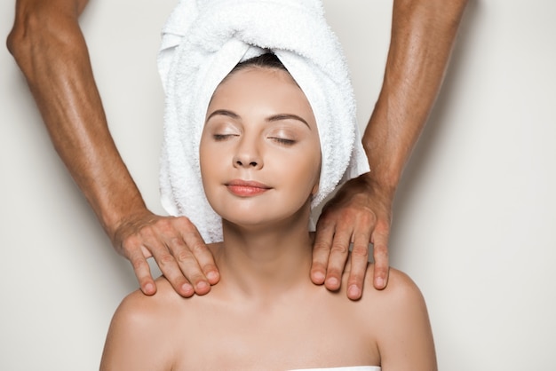 Hands doing massage young beautiful woman in towel