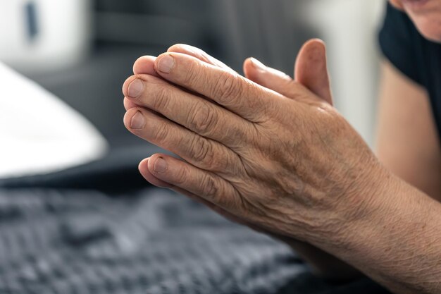 The hands of an elderly woman folded in prayer