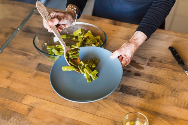 Hands of elderly woman putting tasty dish on plate