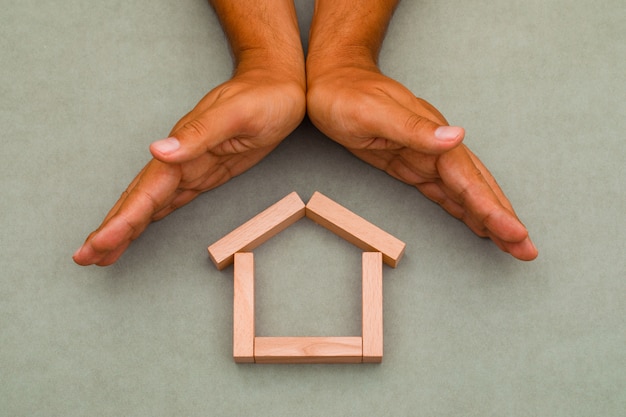 hands enclosing wooden house.