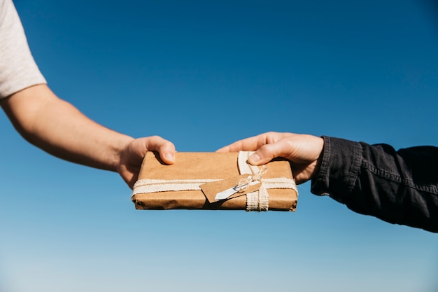 hands exchanging present on sky background