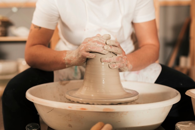陶器のホイールに土製の瓶を作成する女性陶工の手
